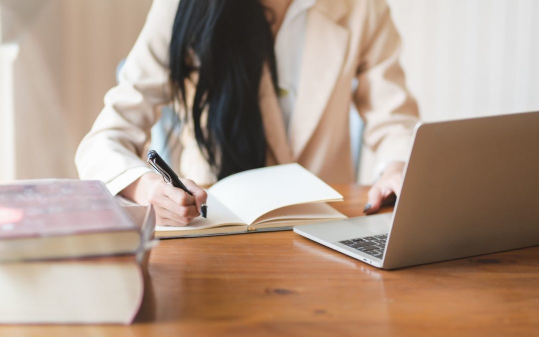 women taking notes looking at a computer