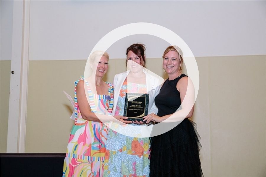 Tracey accepting her award with Whitney and Stephanie with a play sign over it